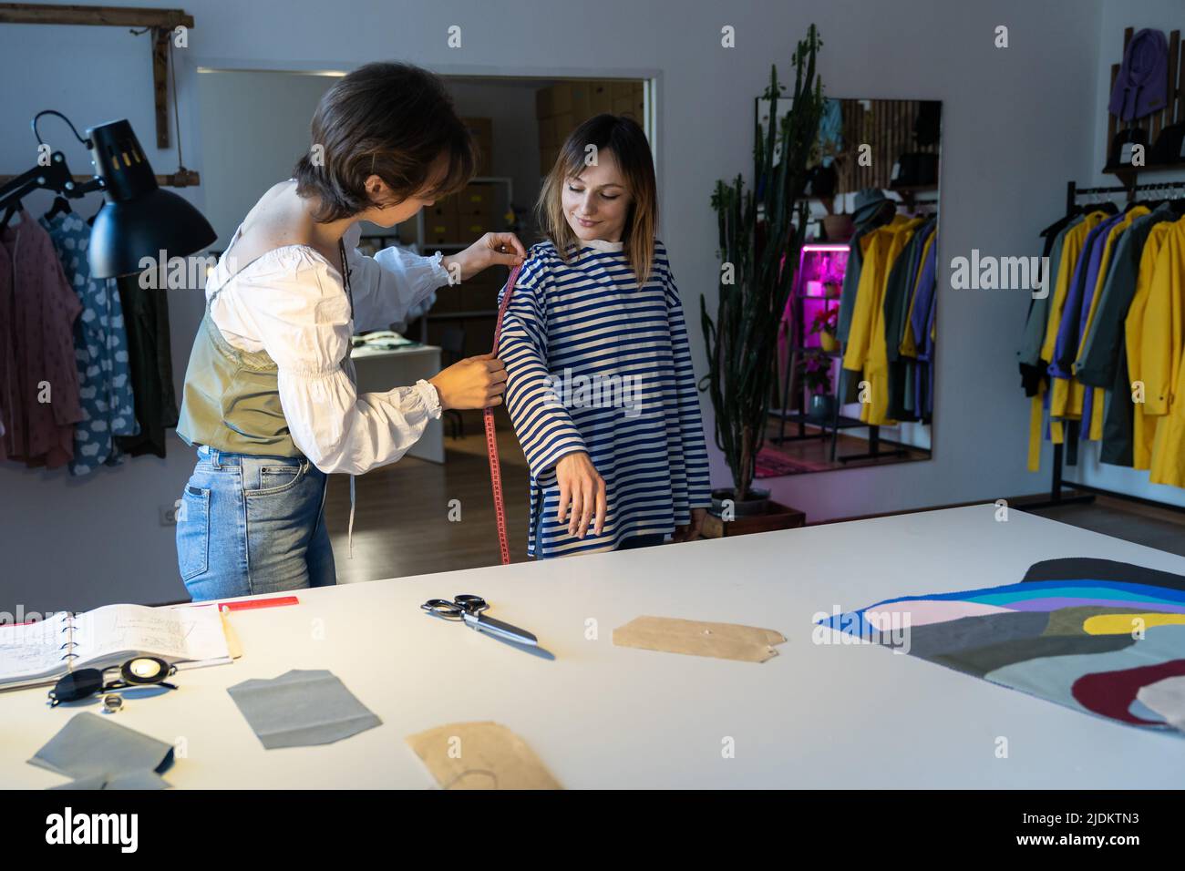 Fashion designer woman takes measurements with measuring tape of client ...