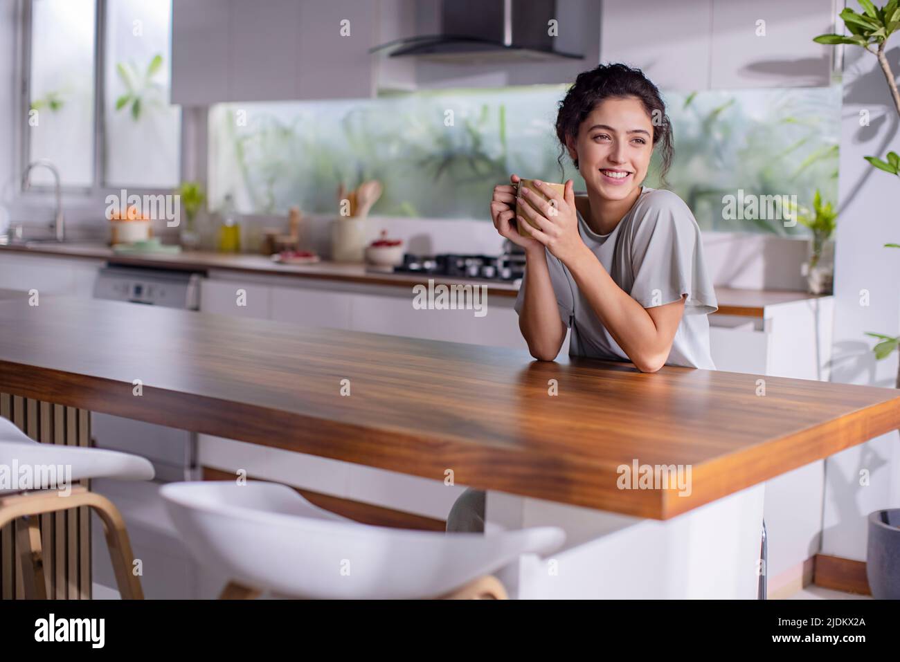 Young woman drinking cup of tea in kitchen  Stock Photo