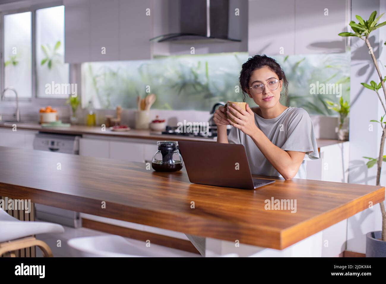 Young woman working on laptop and drinking cup of tea at home Stock Photo