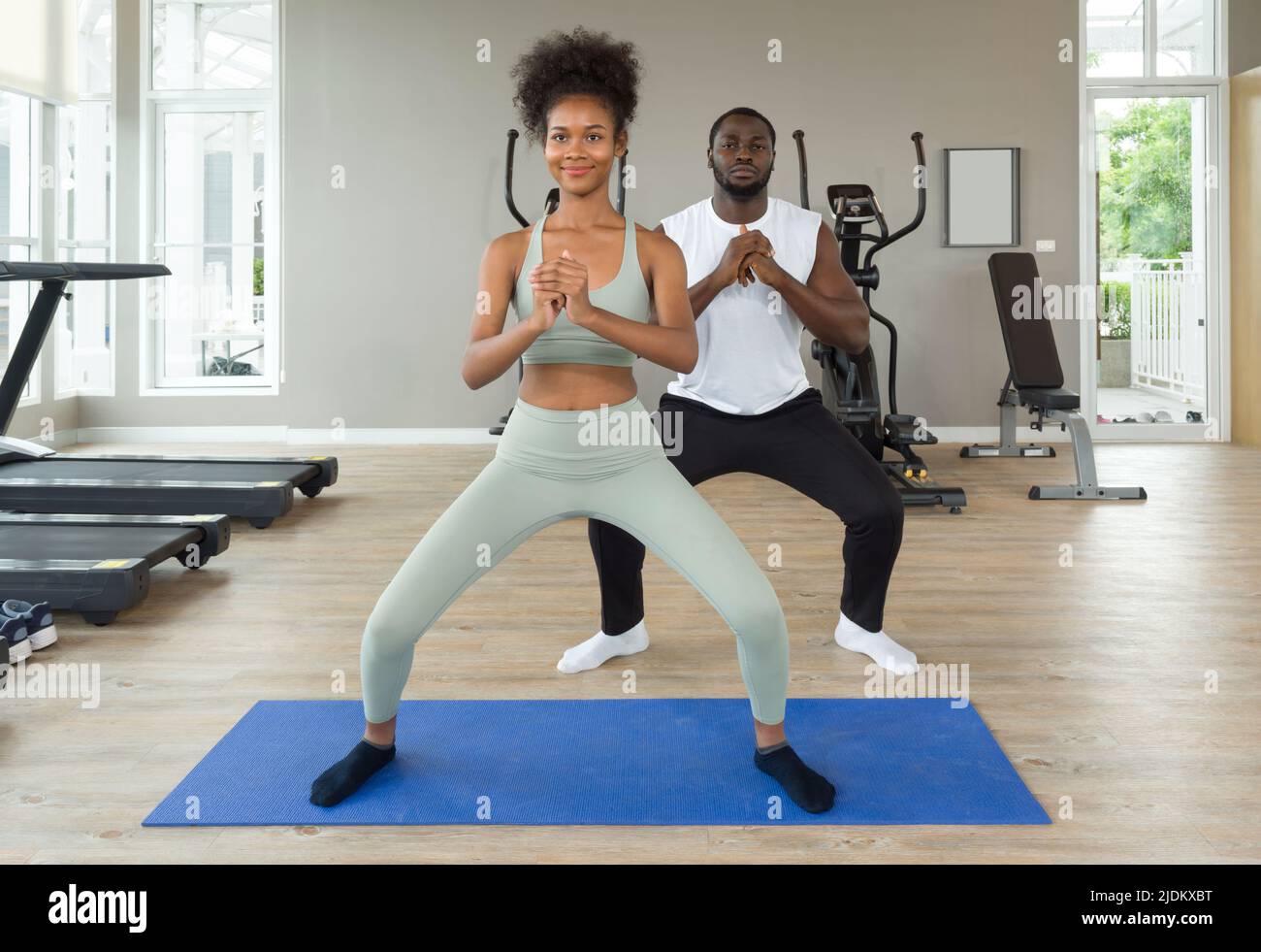 Young curly black hair instructor in sportswear leading exercise class