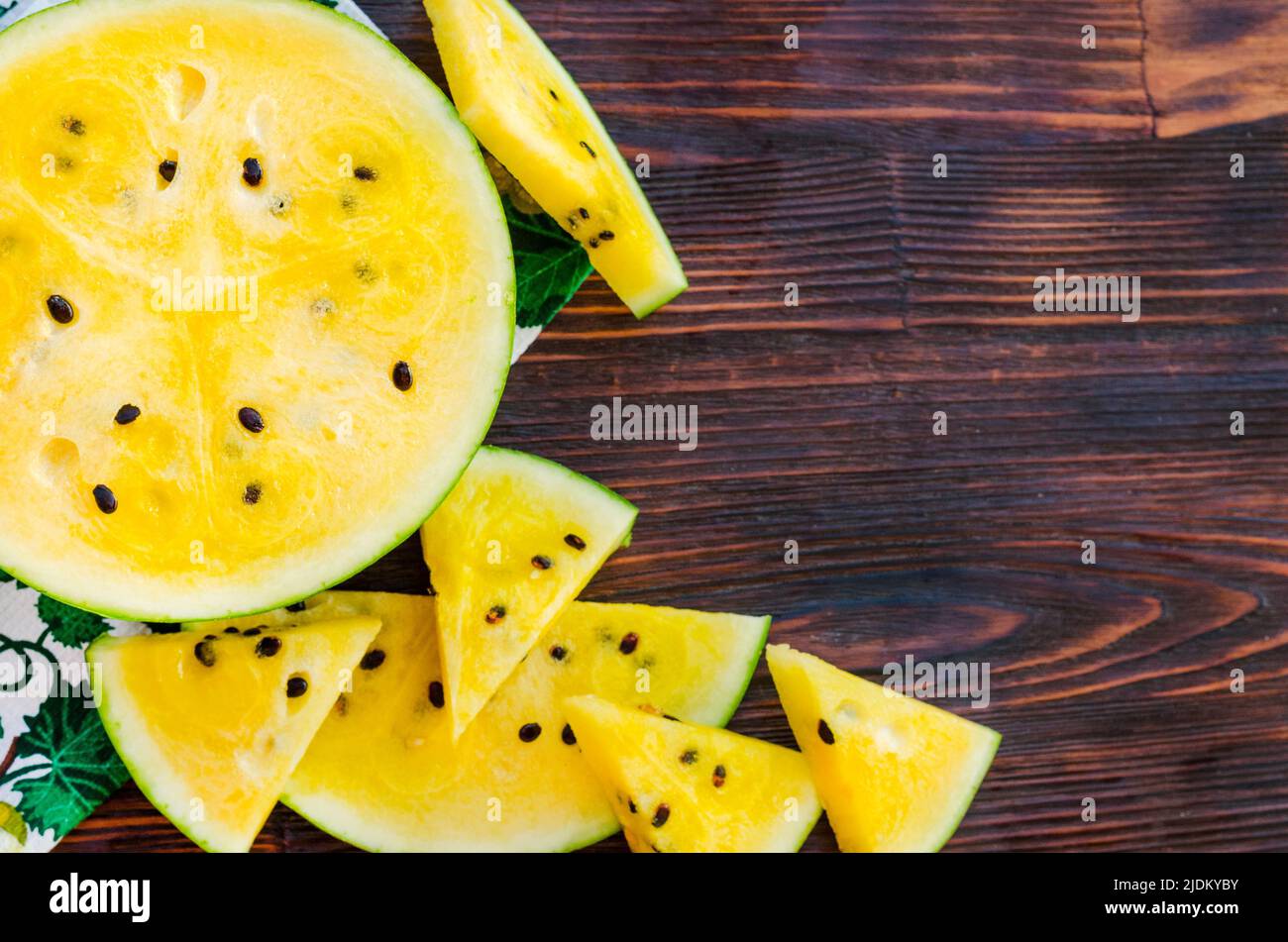 Watermelon with yellow pulp. Sliced pieces of berries on a wooden table. Stock Photo