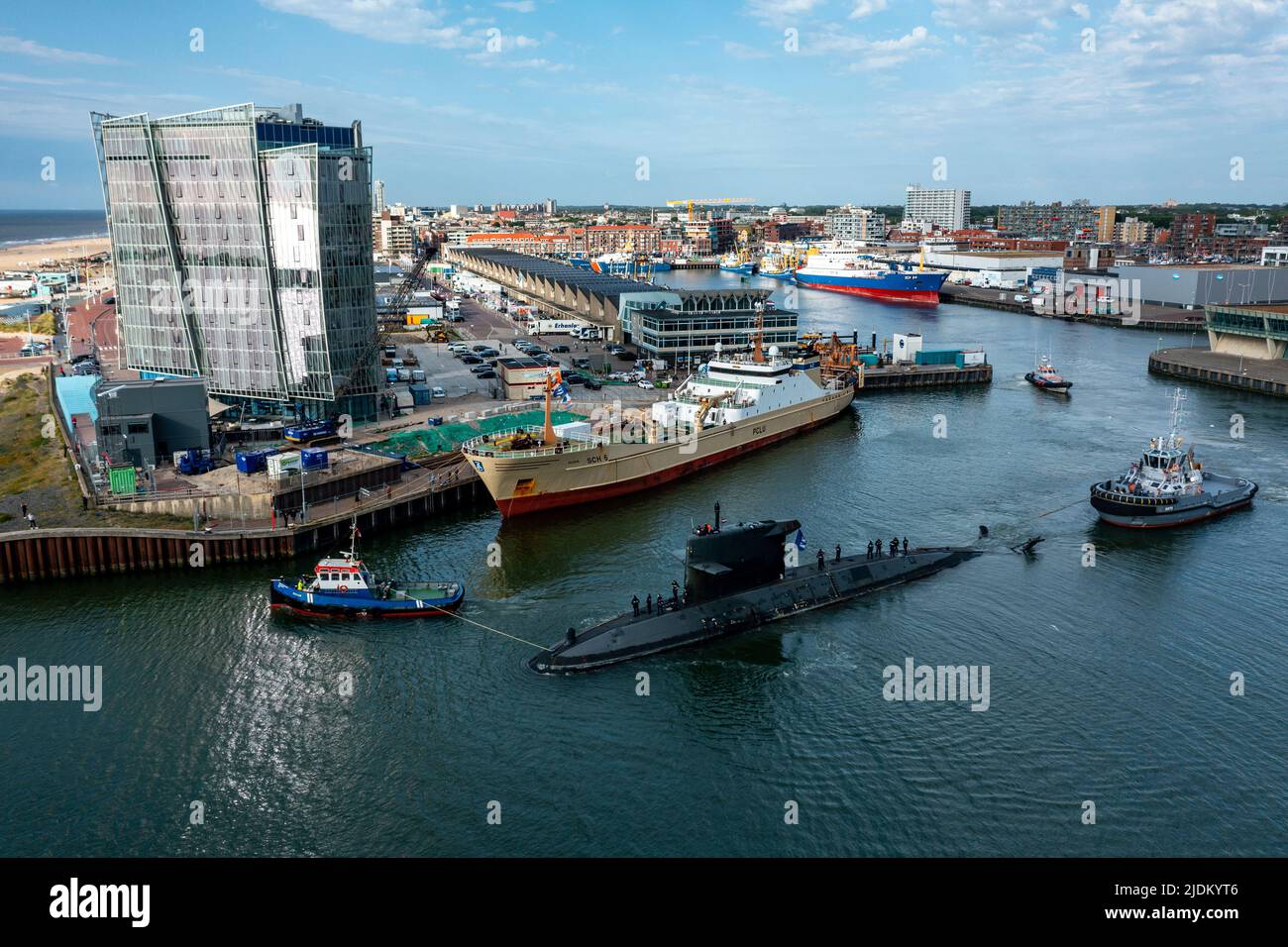 Aerial view of Zr. Ms.Zeeleeuw submarine leaving Scheveningen Harbor, escorted by a navy tugboat, pilot boat & lifeboat, South Hollands, Netherlands. Stock Photo