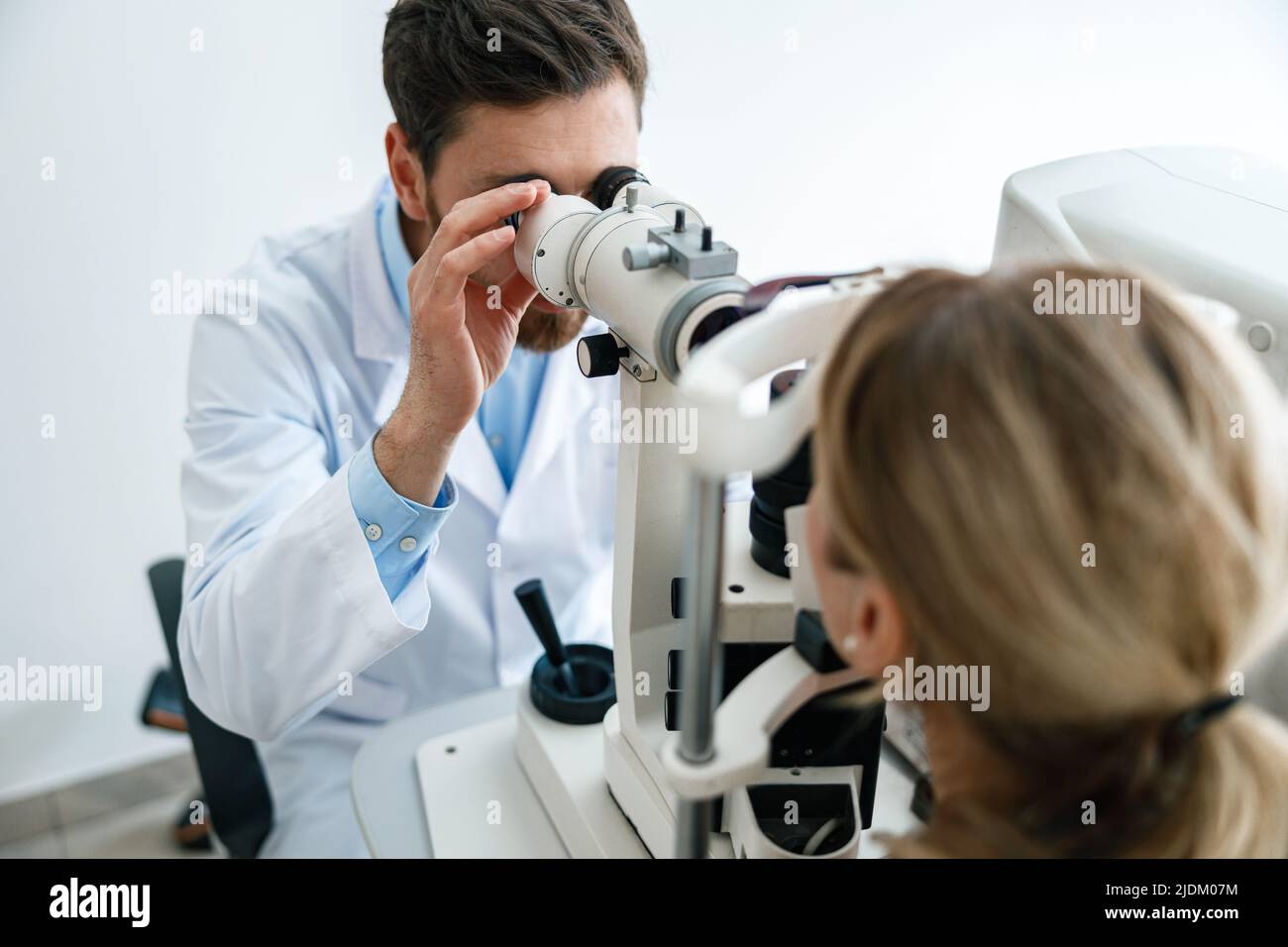 Optometrist checks the patient's intraocular pressure in optician's shop or ophthalmology clinic Stock Photo