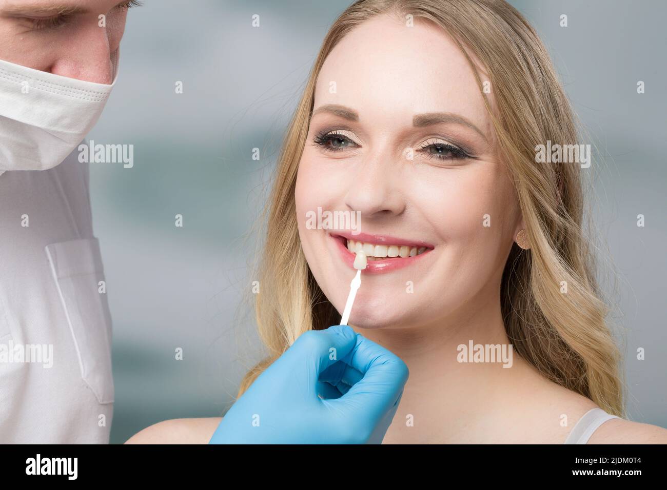 Close up of dentist using shade guide at woman's mouth to check shade