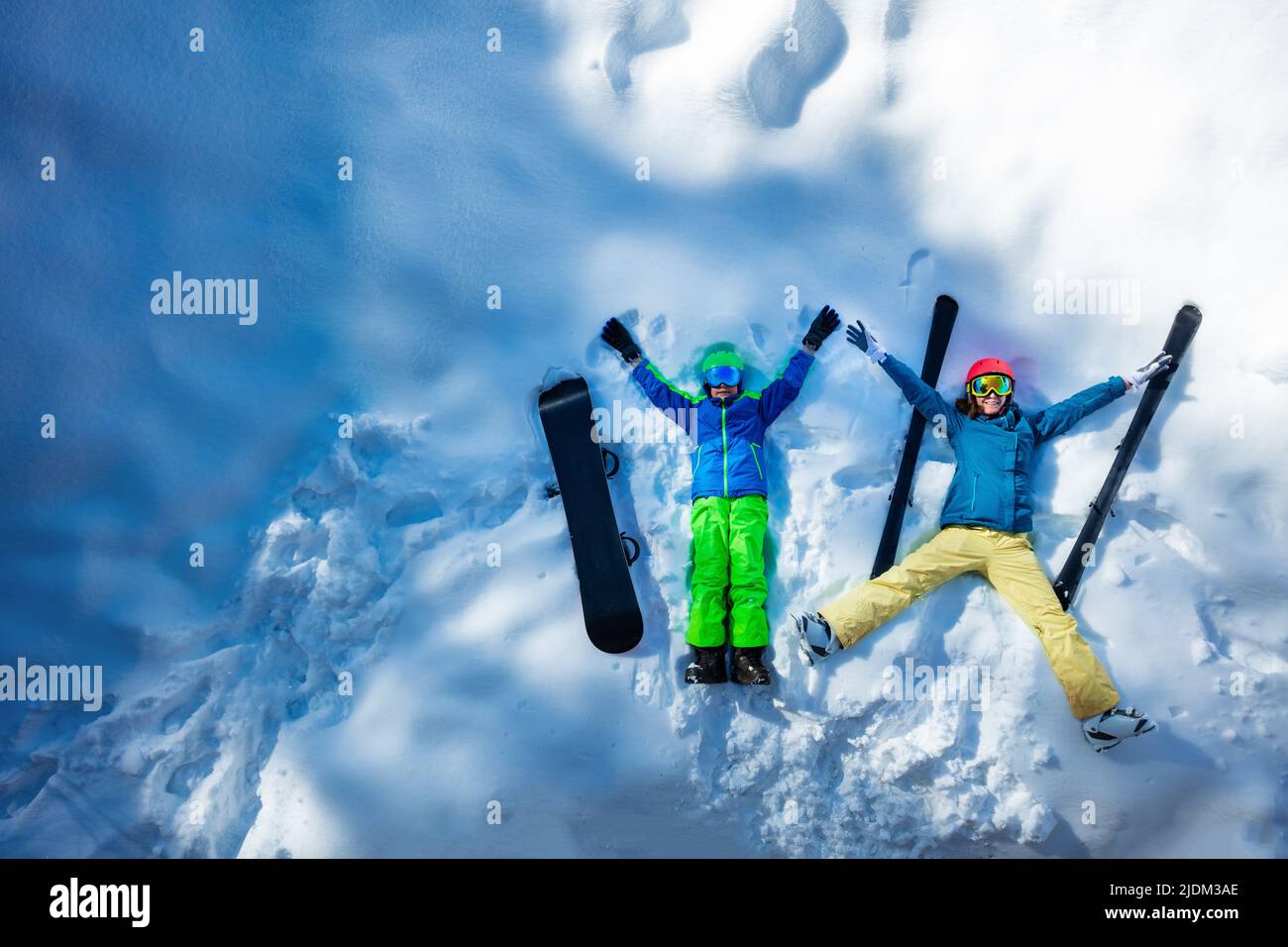 Mother and a boy lay in snow, wear ski outfit, view from above Stock Photo