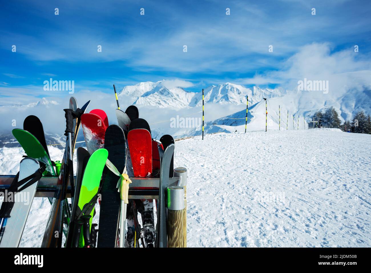 Many different alpine skis over mountain peaks and clouds Stock Photo