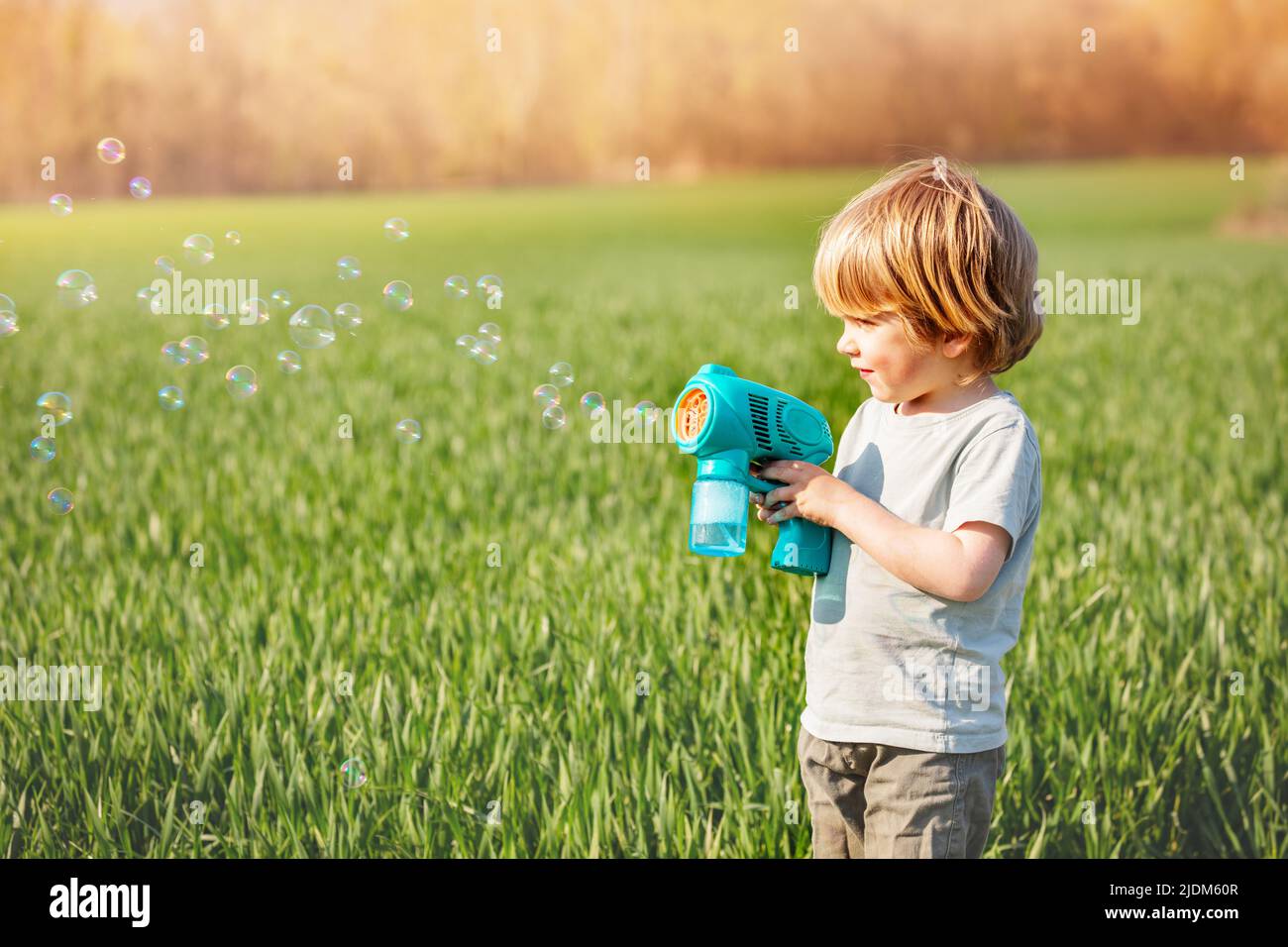 Boy play soap bubbles standing together over spring green field Stock Photo