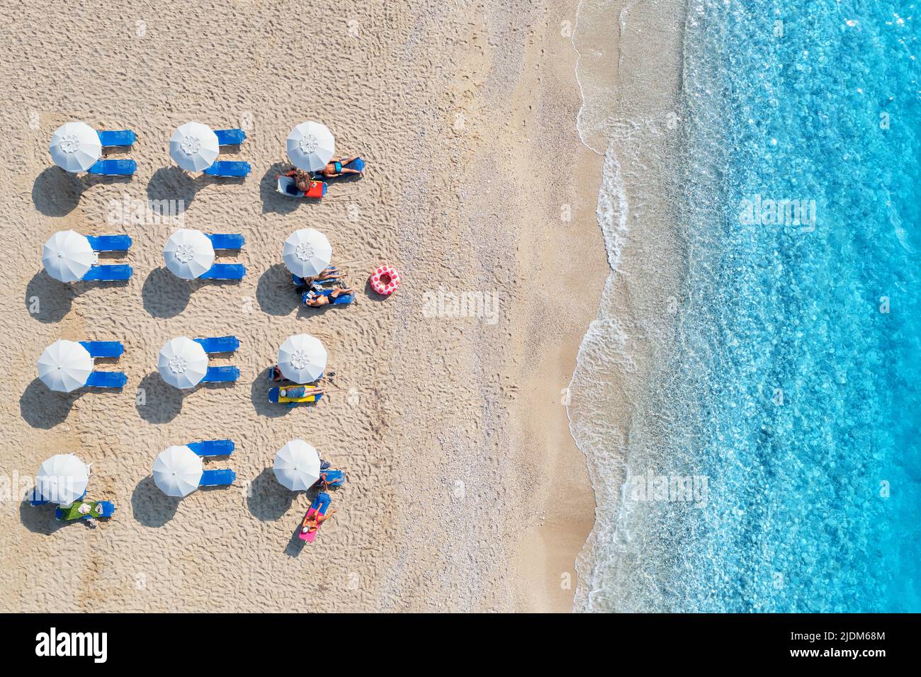 Aerial view of blue sea, sandy beach with umbrellas at sunset Stock Photo
