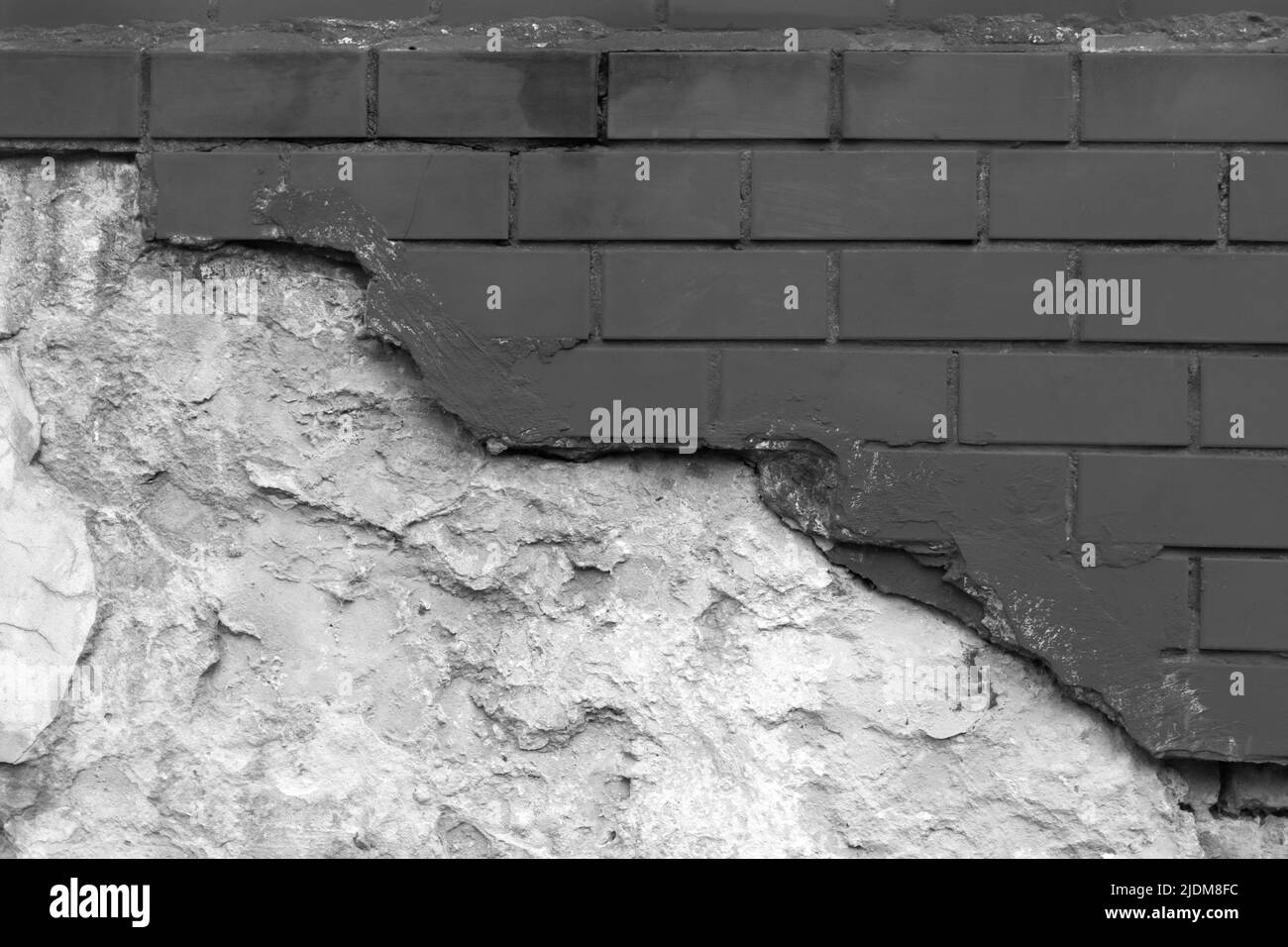 Dark black paint on brick broken masonry wall with cement white grey