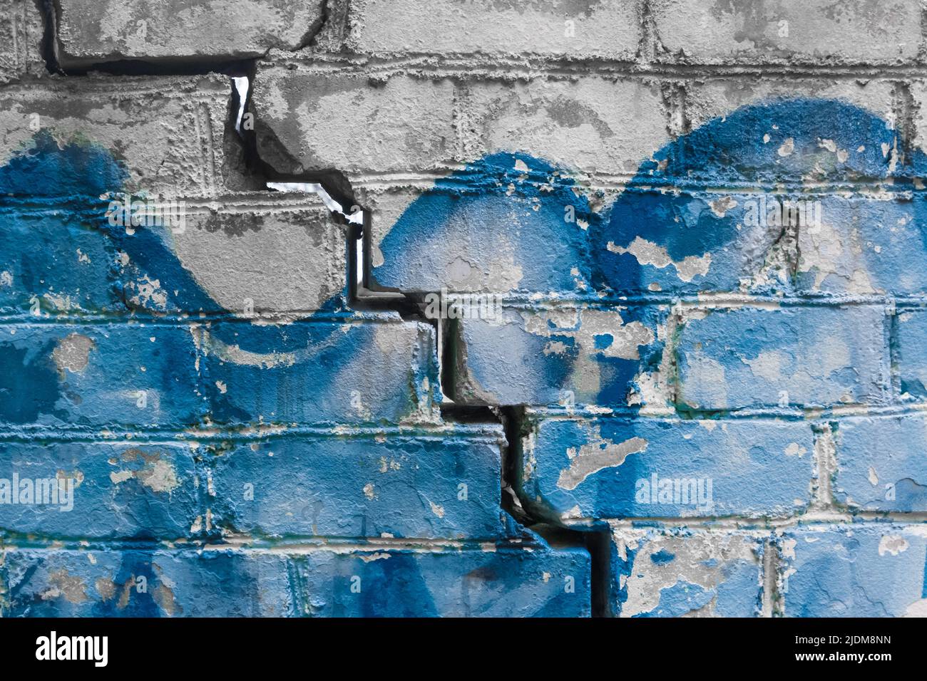 Crack on old brick broken wall with blue paint texture damaged