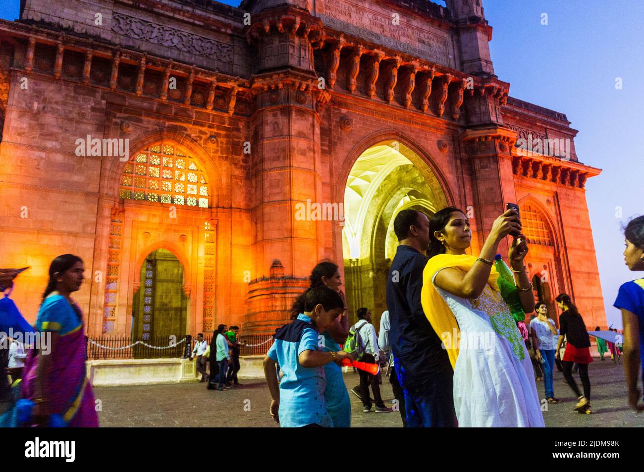 Mumbai, Maharashtra, India : People pose for selfies at dusk in front of the illuminated Gateway of India monumental arch built betwen 1913 and 1924 i Stock Photo