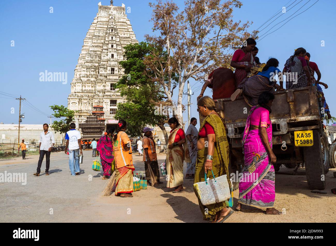 Hampi, Karnataka, India: A colourful group of women boards a lorry in front of the Sree Virupaksha Temple. Believed to be uninterruptedly functioning Stock Photo
