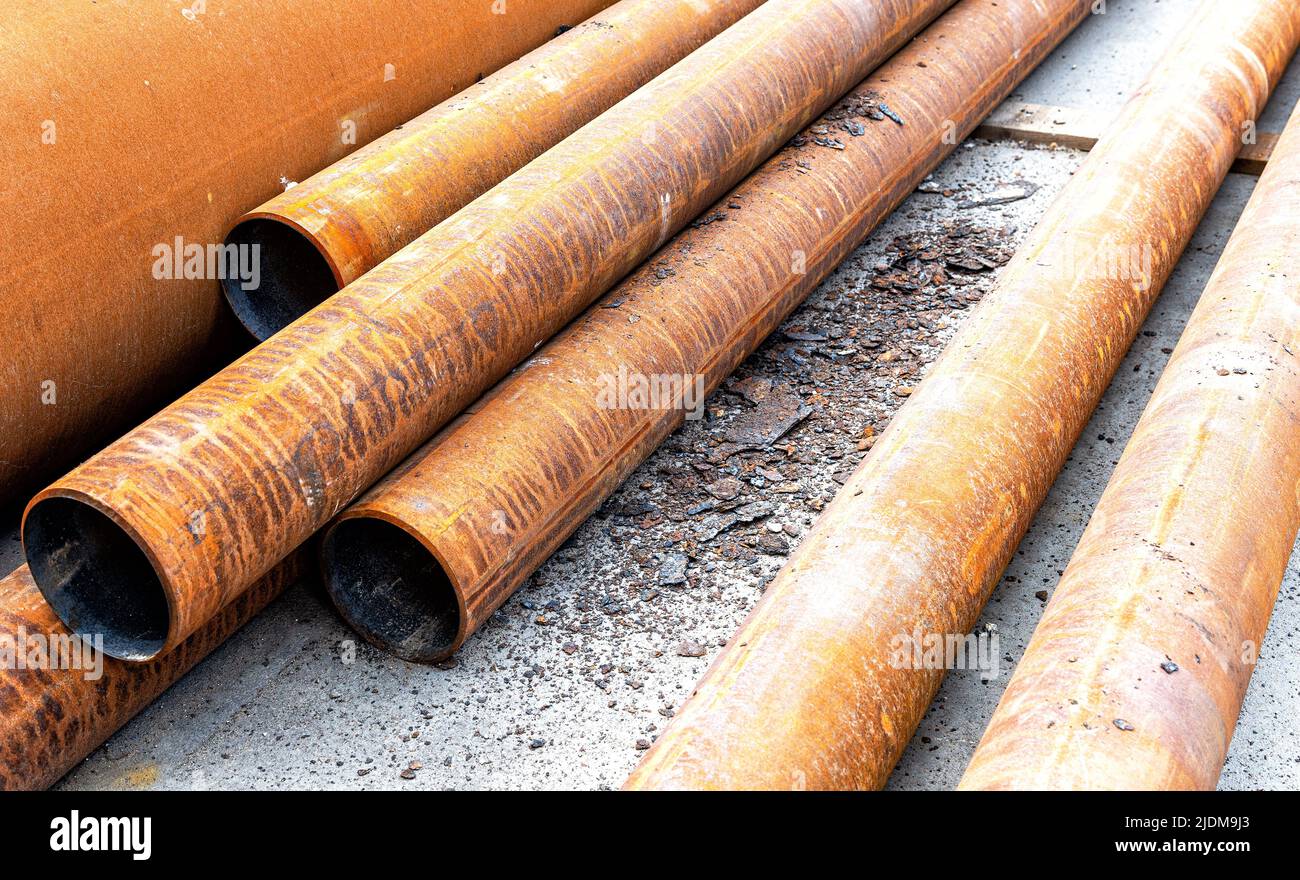 Metal pipes covered with rust lie on the construction site. Construction work in progress Stock Photo