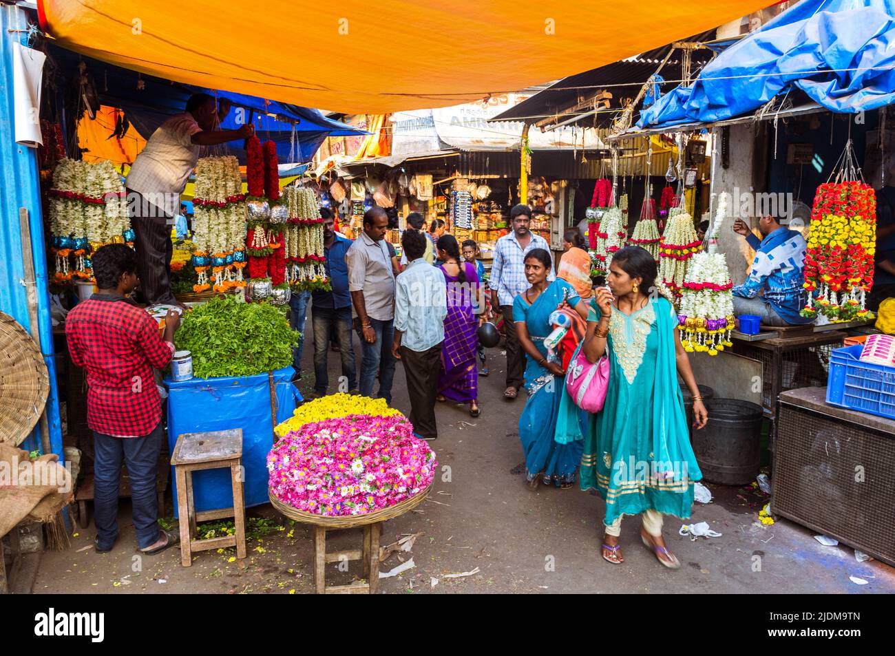 Mysore, Karnataka, India : Women walk past flower stalls at the Devaraja market. Stock Photo