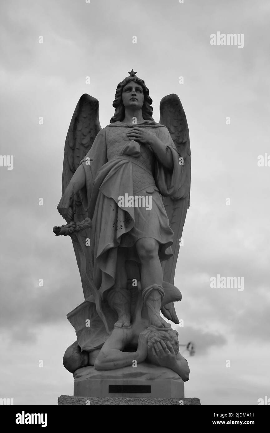 St Michael the archangel standing triumphant over his defeat of Satan in black and white. Stock Photo