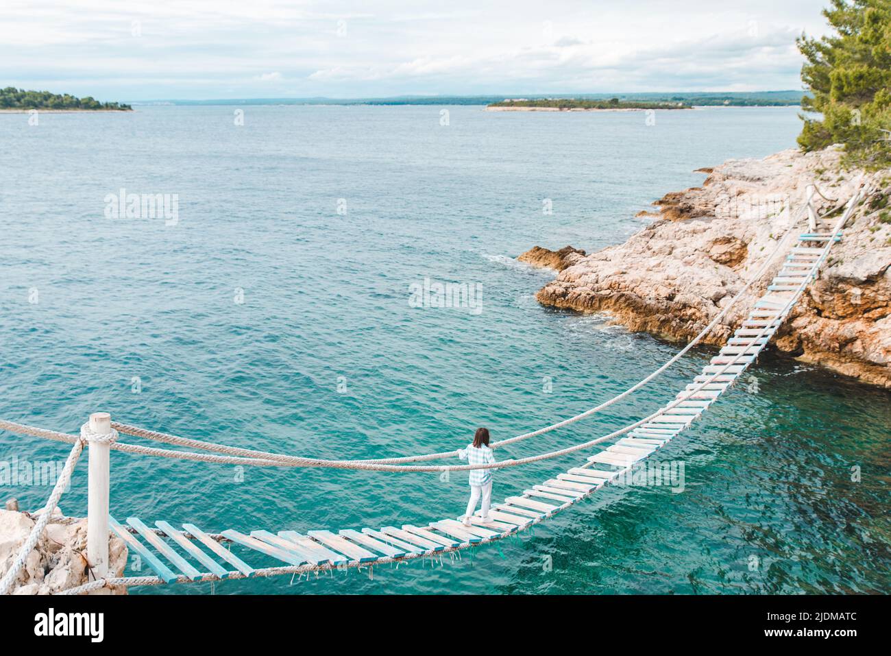 woman crossing suspension bridge sea on background Stock Photo - Alamy