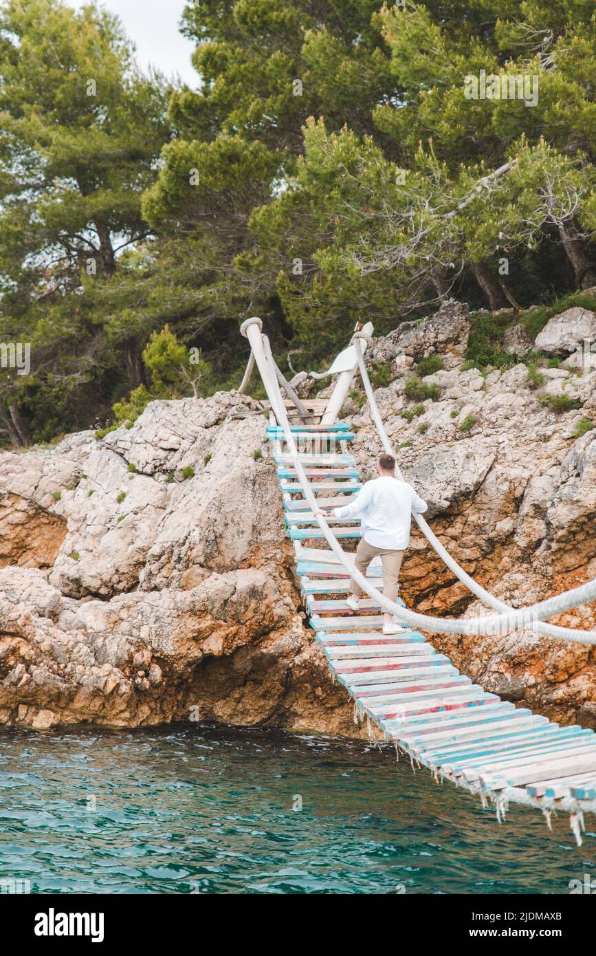 man walking by suspension bridge Stock Photo - Alamy