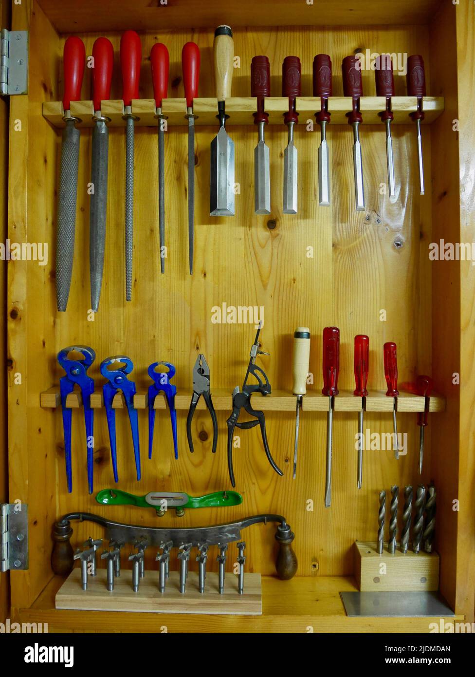 Wooden tool cabinet filled with technician equipment in home workshop. Stock Photo