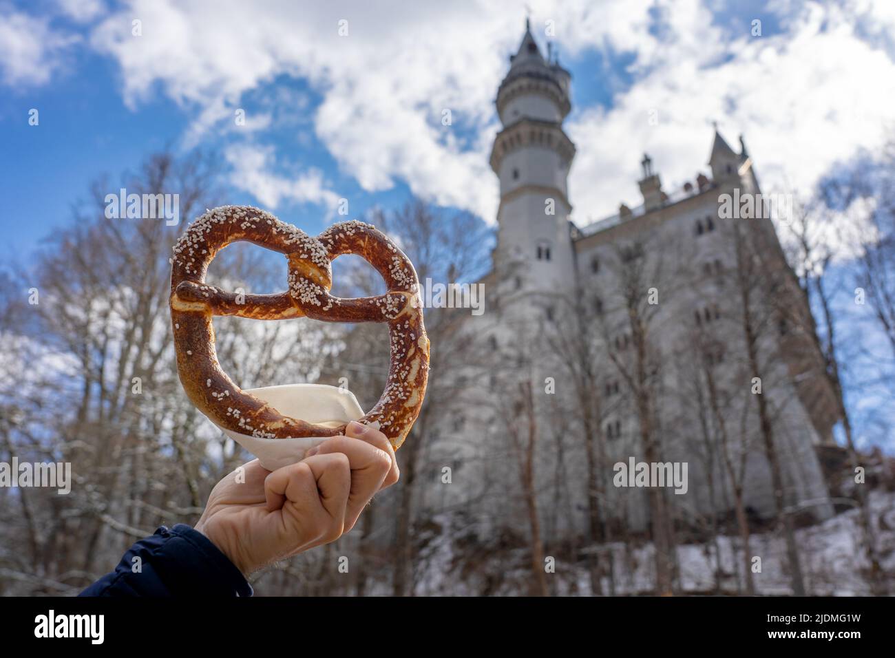 eating huge bavarian pretzel next to the Neuschwanstein castle Stock Photo