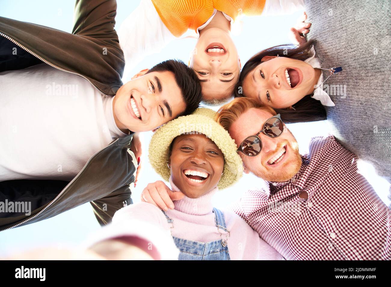 Smiling low angle circle selfie of cheerful group of young people. Happy friends excited having fun. Boys and girls taking picture looking at camera Stock Photo