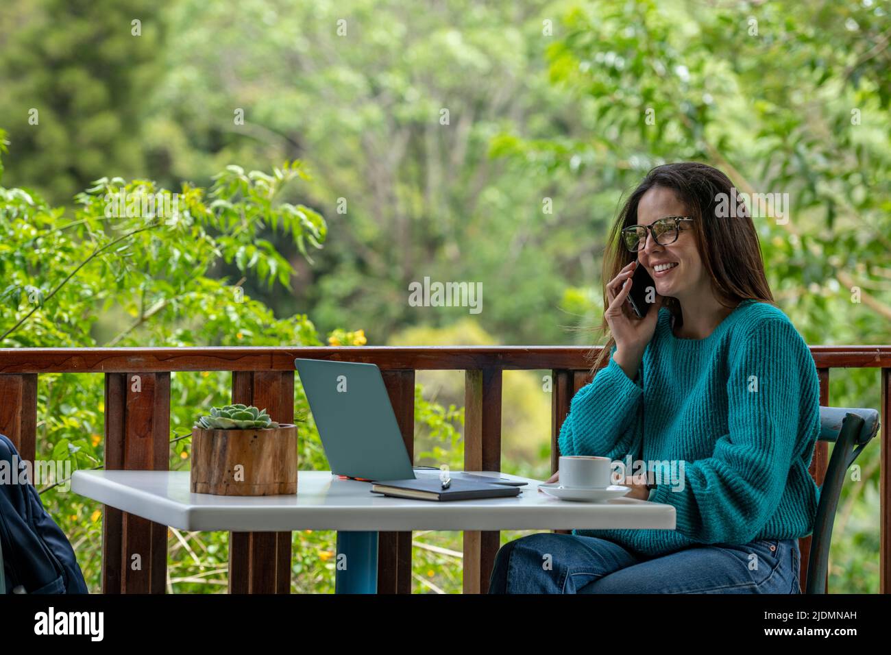 Young Latin American woman working on her laptop at a outdoor cafe while drinking a cup of coffee, Panama, Central America Stock Photo
