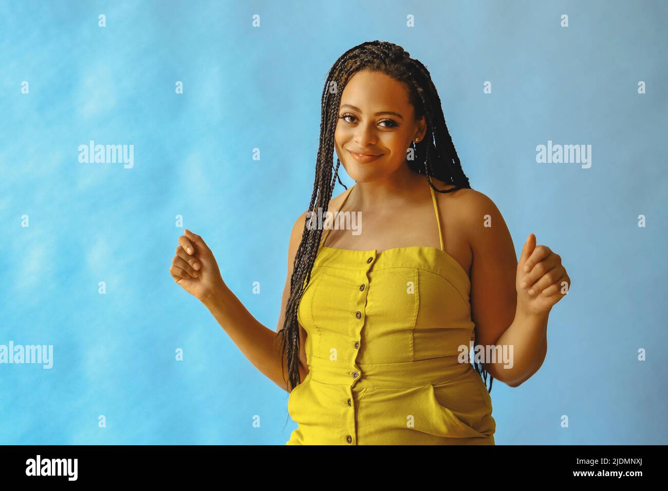 portrait of young adult beautiful african american woman smiling and dancing with braid hair posing at studio shot Stock Photo