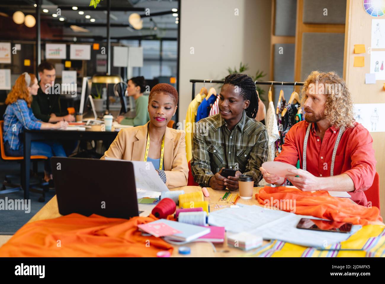 Multiracial male and female fashion designers discussing over document ...