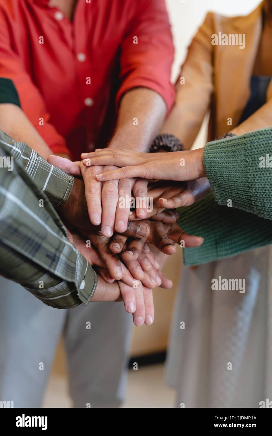 Midsection of multiracial fashion designers stacking hands in office Stock Photo