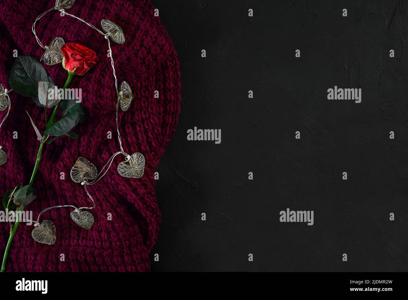 Brown knitted plaid and red rose on black background. Overhead v Stock Photo