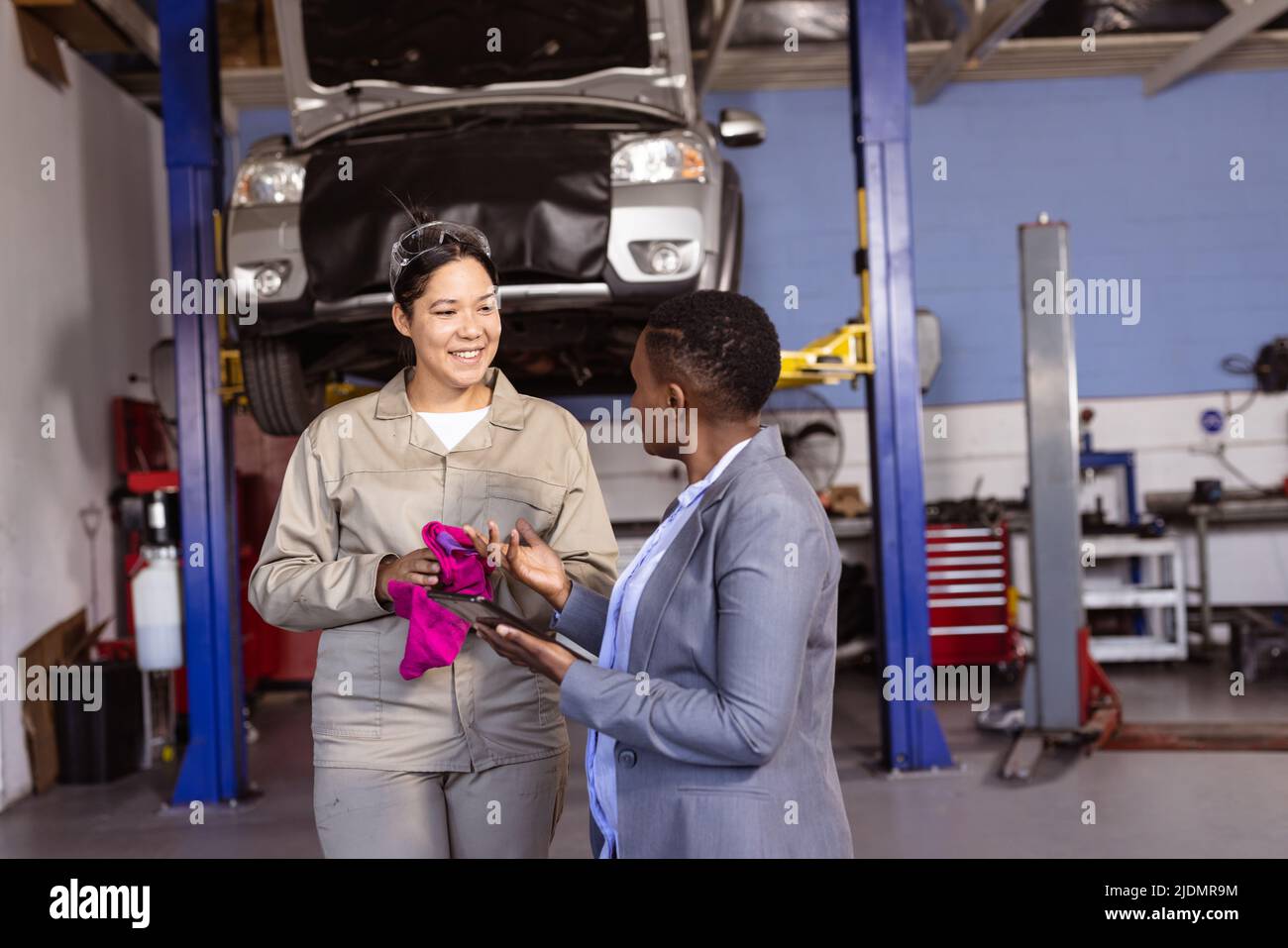 African american female engineer discussing work with smiling asian mid adult colleague, copy space Stock Photo
