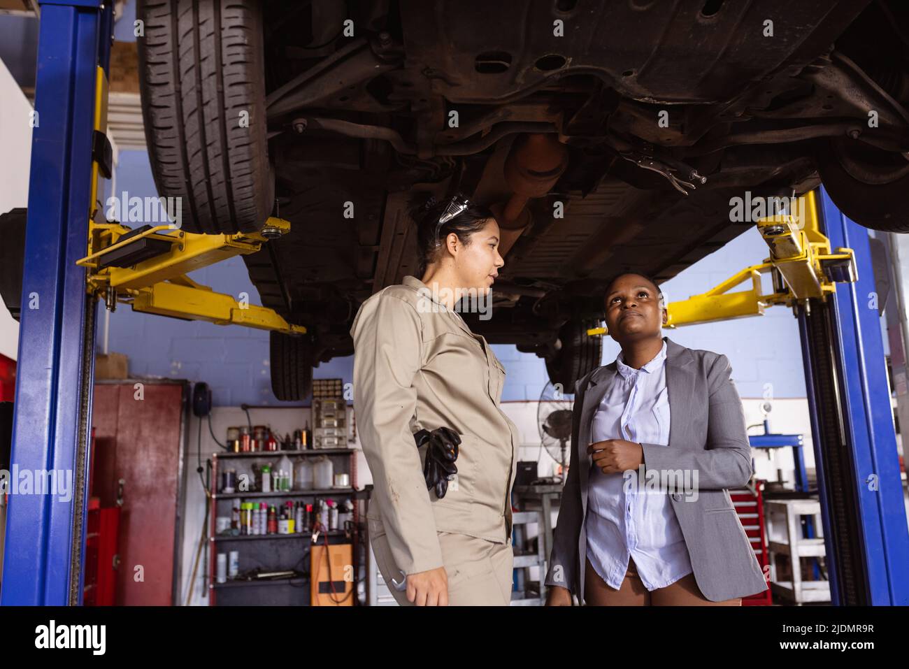 Mid adult multiracial female technicians repairing car in workshop, copy space Stock Photo