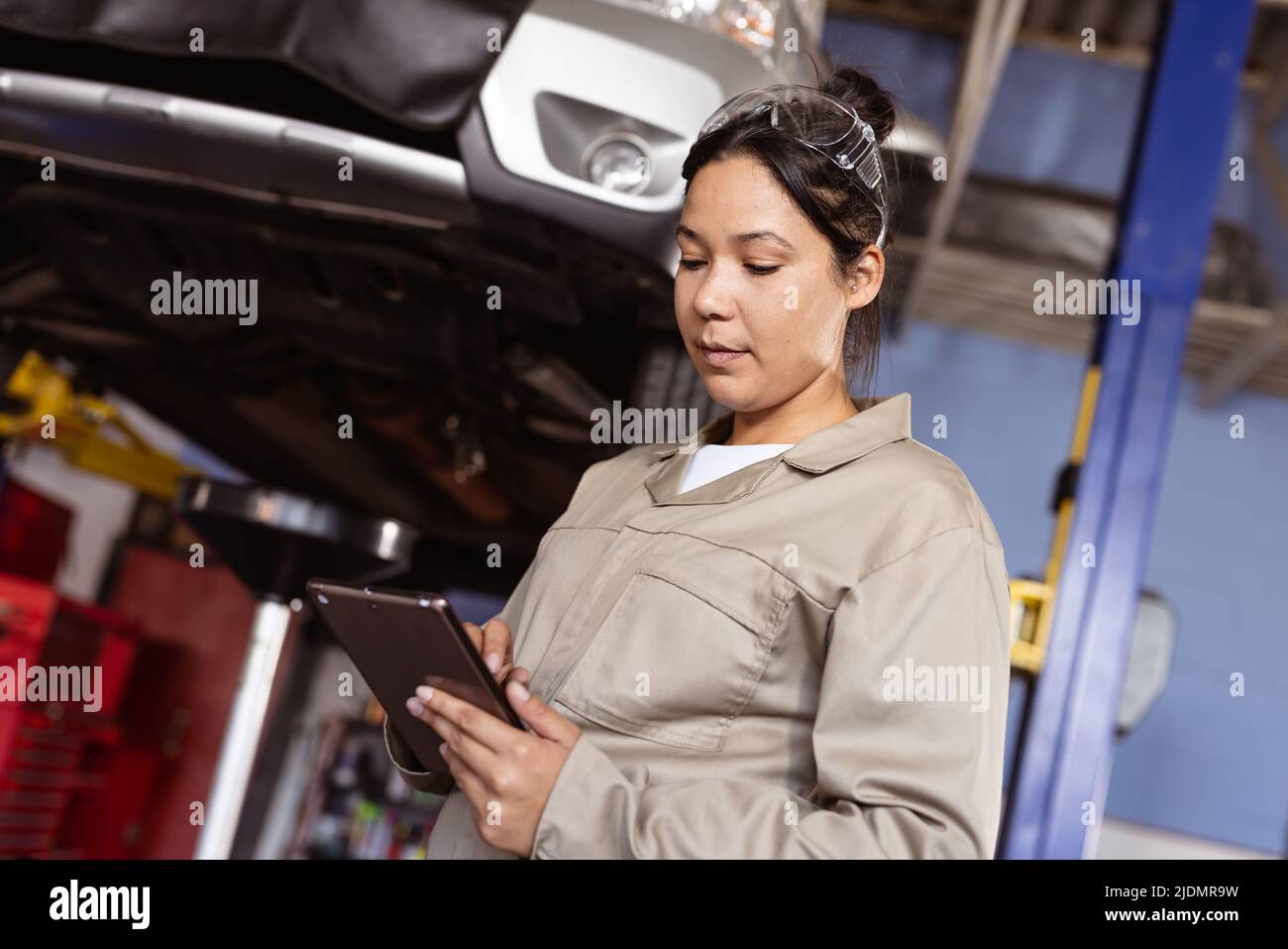 Mid adult asian female engineer using digital tablet while repairing car in workshop, copy space Stock Photo