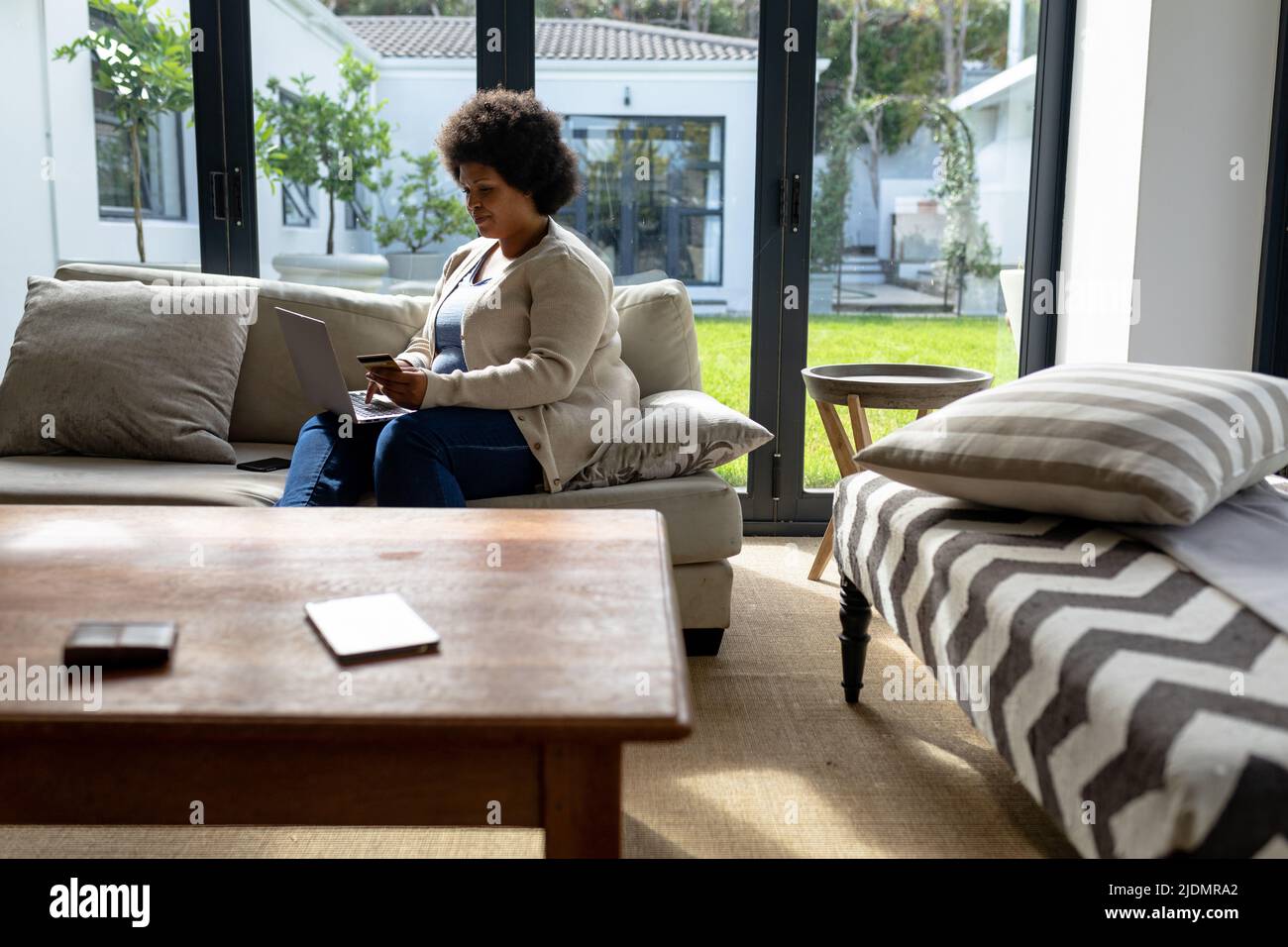 African american woman using laptop while sitting on couch at home ...
