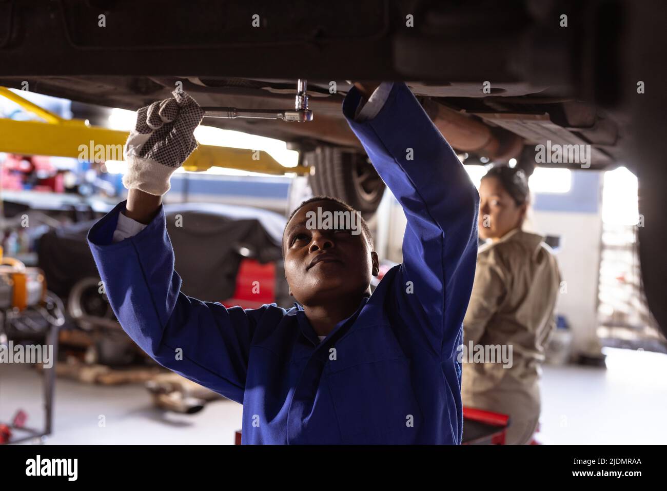 African american mid adult female engineer repairing car with colleague in workshop Stock Photo