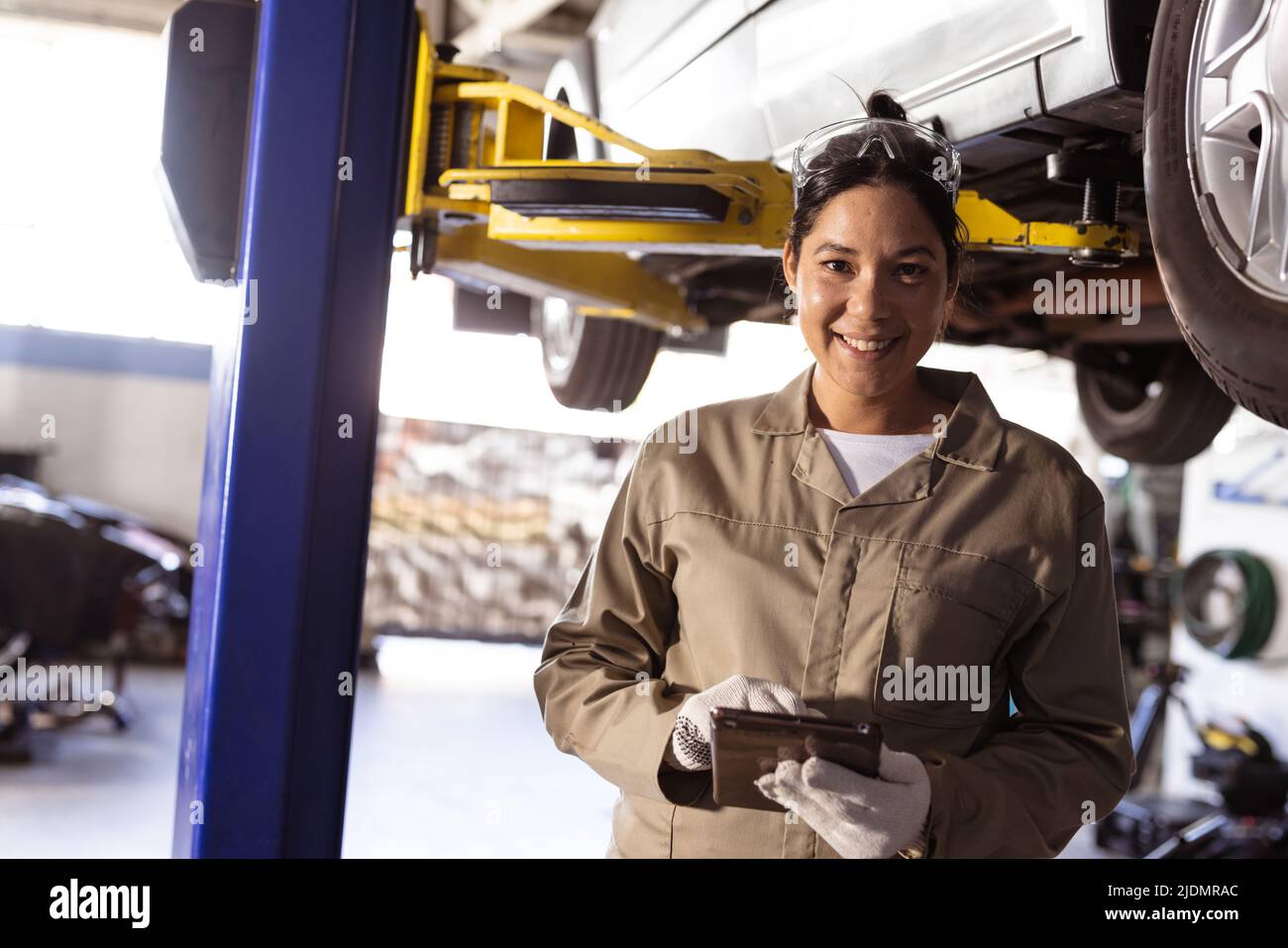 Portrait of smiling mid adult asian female engineer using digital tablet in workshop, copy space Stock Photo