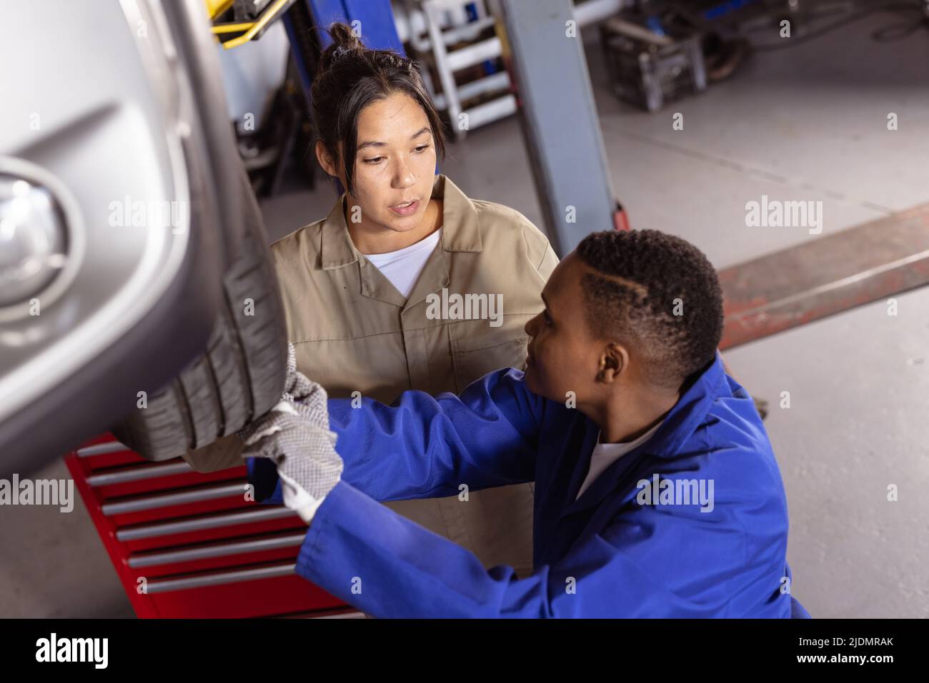 Multiracial mid adult female engineers working together while repairing car in workshop Stock Photo