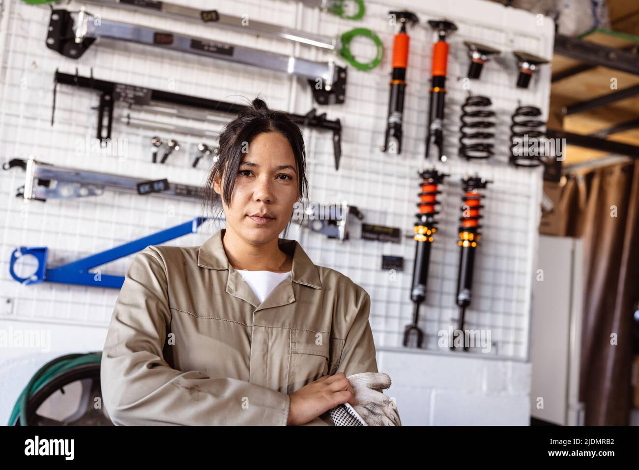 Portrait of confident asian mid adult female mechanic against various work tools in workshop Stock Photo