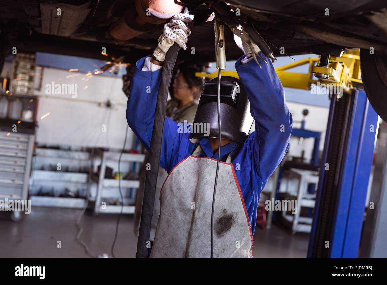 African american mid adult female welder welding car while working in workshop, copy space Stock Photo