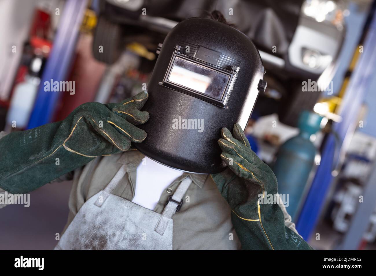 Mid adult asian female welder wearing protective mask and gloves while working in workshop Stock Photo