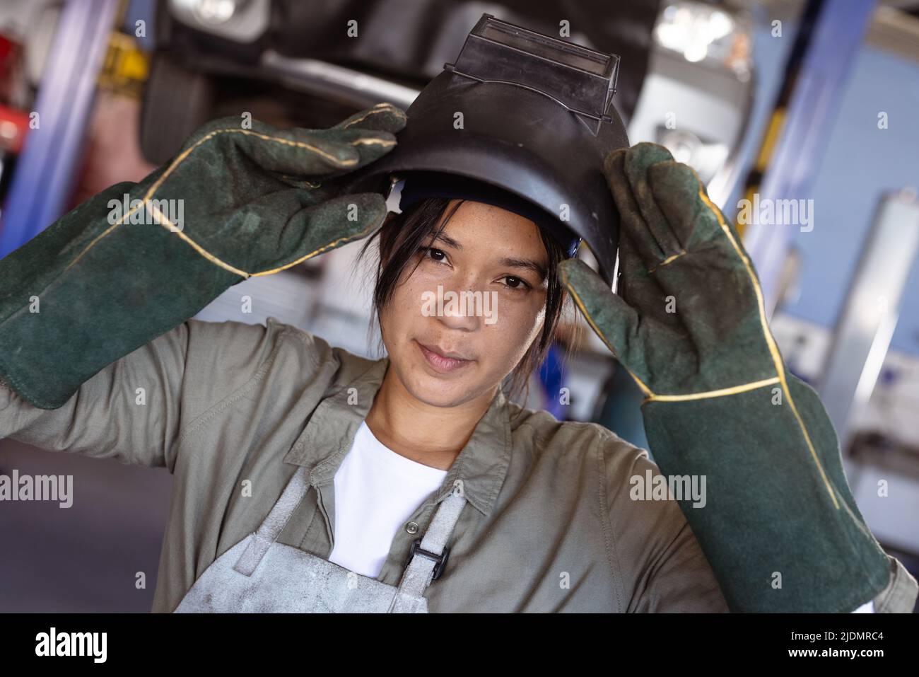 Portrait of confident mid adult asian female welder wearing protective workwear in workshop Stock Photo