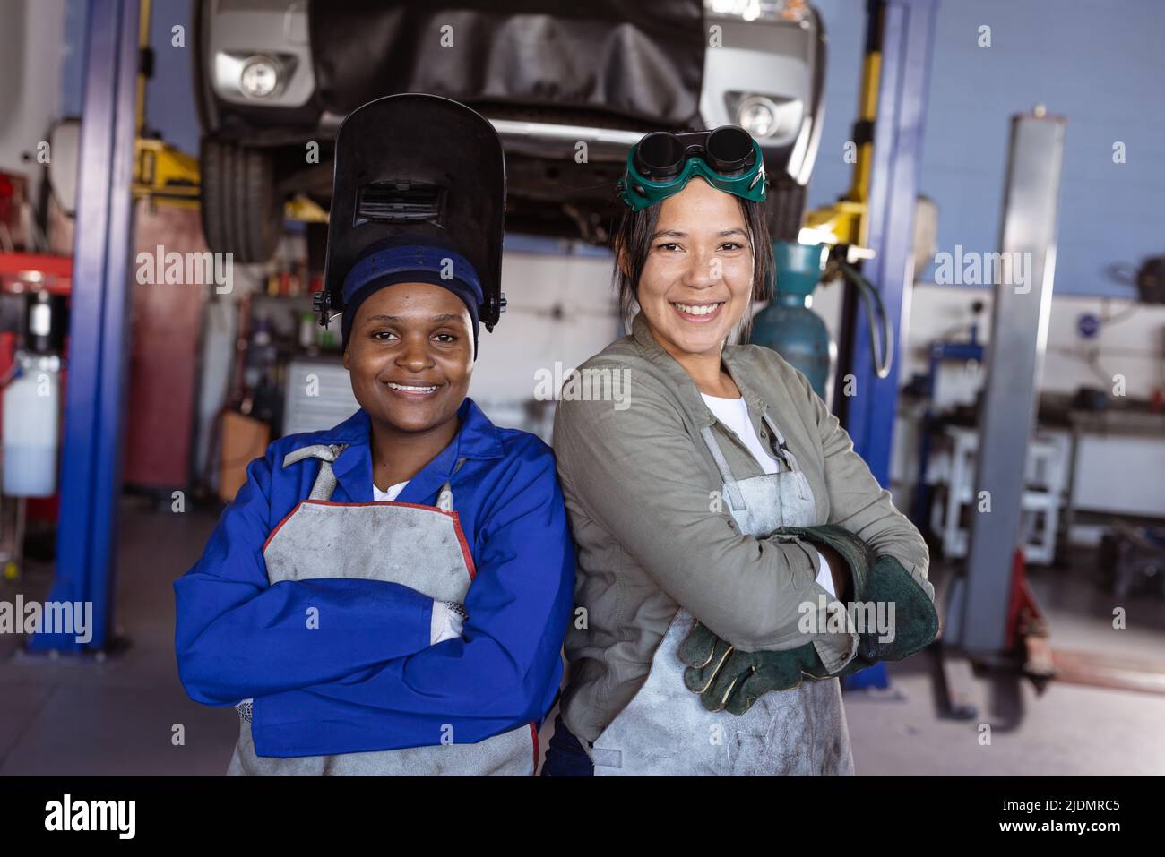 Portrait of confident smiling mid adult multiracial female welders working in workshop Stock Photo