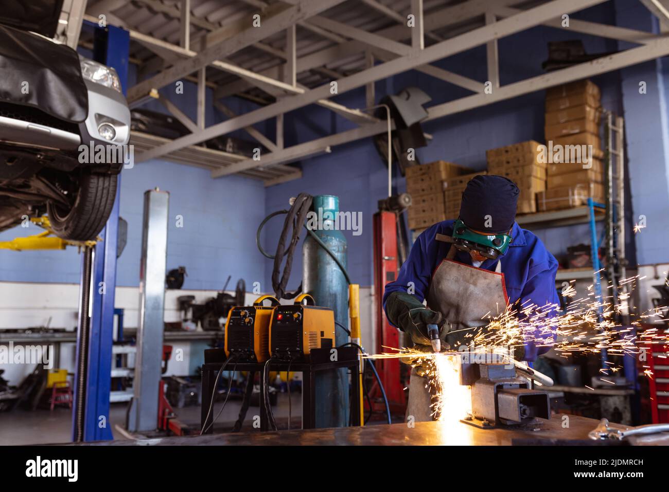 Mid adult african american female welder wielding car's part while working in workshop Stock Photo