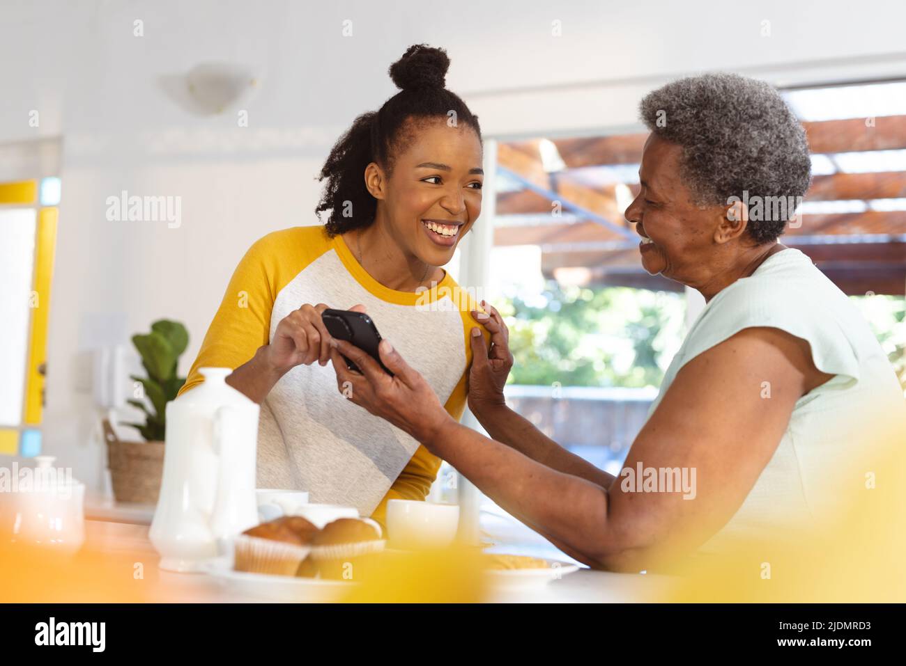 Happy african american senior woman showing smartphone to daughter ...