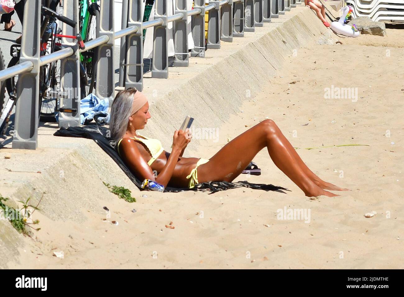 Boscombe, Bournemouth, Dorset, UK, 22nd June 2022, Weather. Hot afternoon in glorious summer sunshine. Woman sunbathing on the beach in a yellow bikini. Credit: Paul Biggins/Alamy Live News Stock Photo