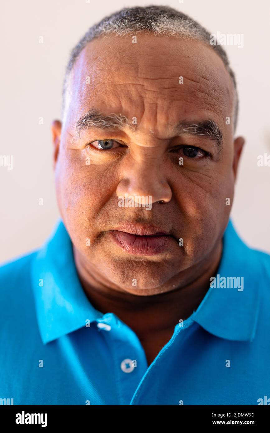 Close-up portrait of biracial senior man with gray eyes against wall in retirement home Stock Photo