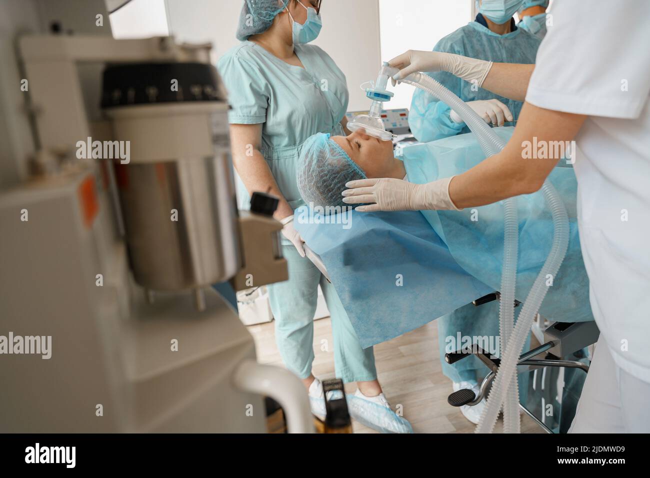 Close up hands of doctor anesthesiologist holding breathing mask on patient face during operation Stock Photo