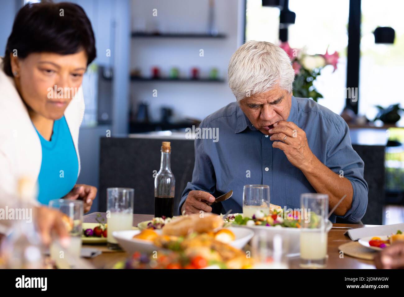 Biracial senior man and woman eating food while sitting at dining table in nursing home Stock Photo