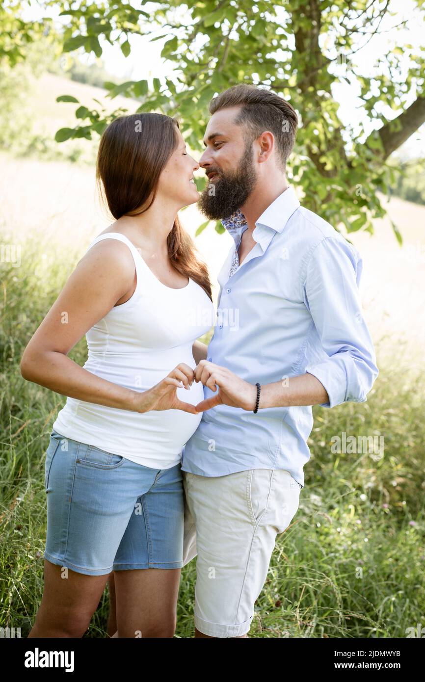 pretty young pregnant woman with white shirt stands with her boyfriend