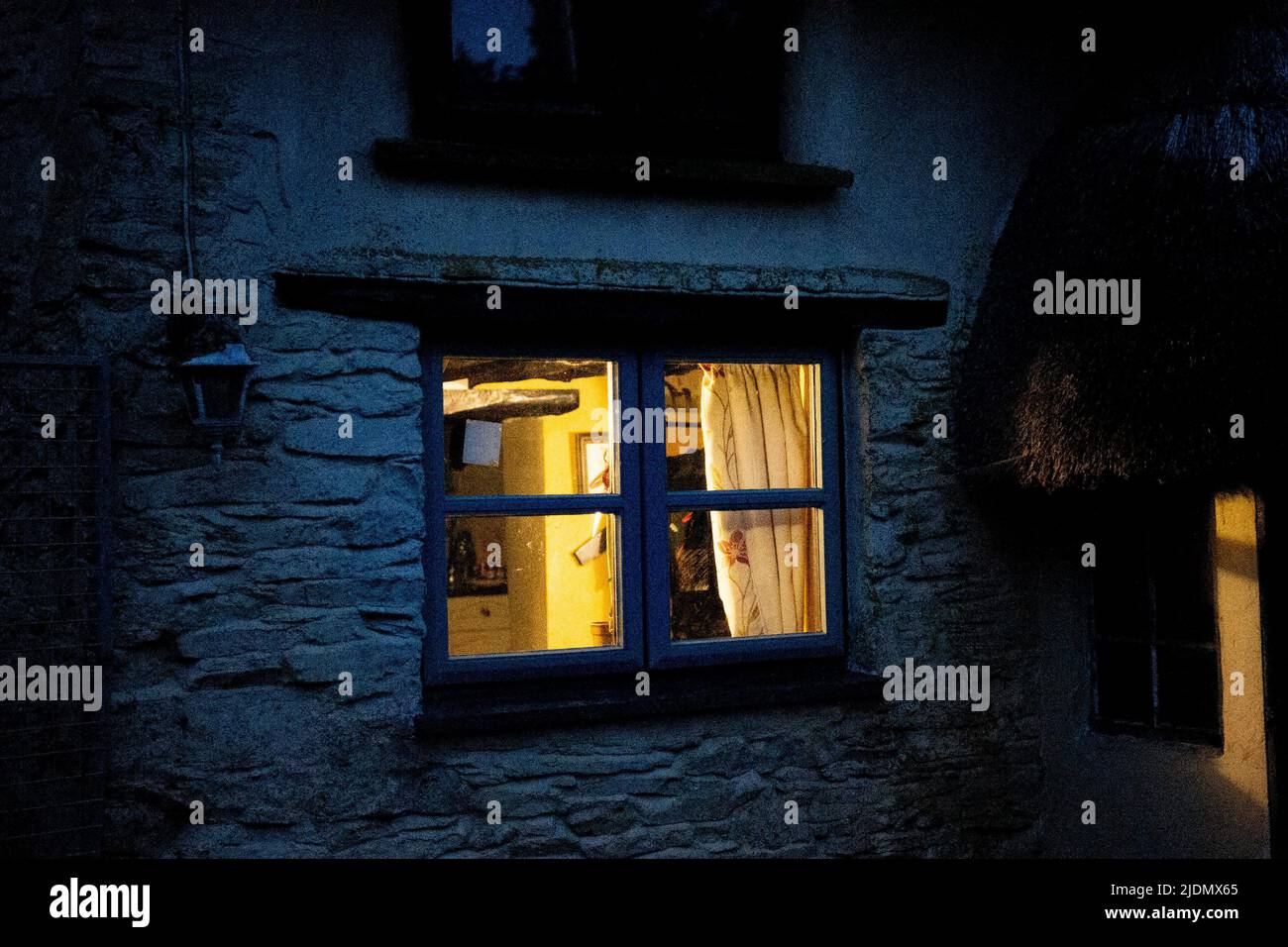 old cottage at night with lights on Stock Photo