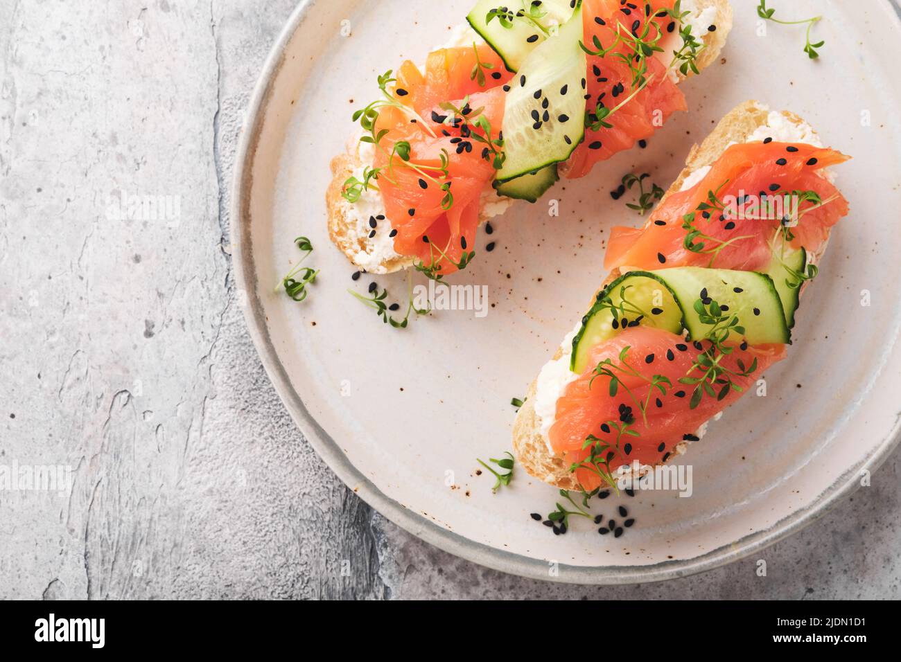 Sandwiches. Salmon toast with cream cheese, cucumber, black sesame and microgreens on gray